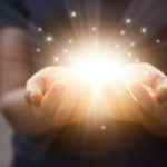 Stardust and magic in woman hands on dark background